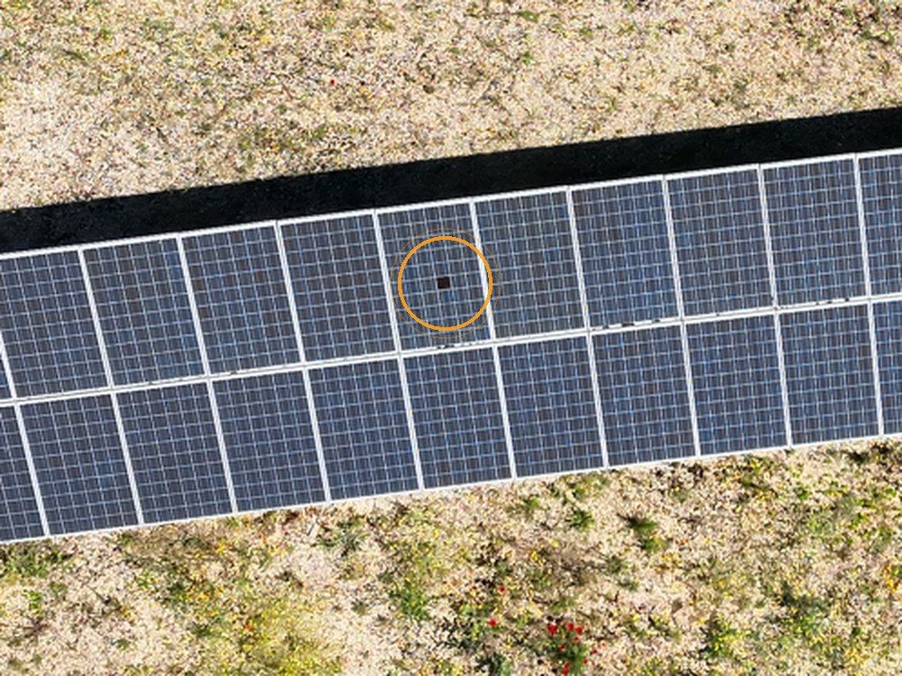Módulo fotovoltaico visto desde el dron con cámara visible: una célula dañada de pocos centímetros, marcada en naranja, casi imperceptible en el conjunto de la planta